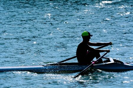 Man rowing a rowboat 	Silhouette of a man rowing a rowboat over a river.の写真素材