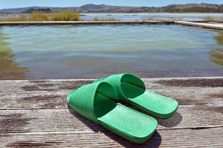 A pair of green jandals beside outdoor hot pool spa in Rotorua, New Zealand.の写真素材