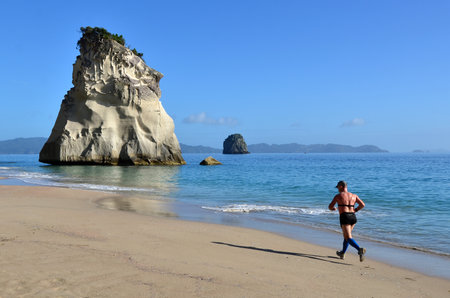 WHITIANGA, NZL - Jan 20 2015: Man runs on the beach of Cathedral Cove.The area is very popular with tourists, and receives around 150,000 visitors per year.のeditorial素材