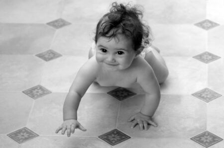 Little baby (girl age 07 months) crawling on the floor. concept photo child development (BW)の写真素材