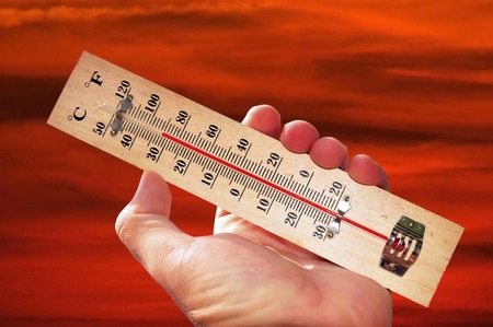 A hand and temperature scale over a red sky shows high temperatures during a heat wave.の写真素材
