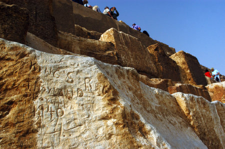 Tourists taking photos and climbing on the great pyramids in Giza, Egypt.