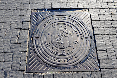 Manhole cover reads in Hebrew: TEL AVIV PORT on Tel-Aviv beach on the coastline of the Mediterranean sea, Israelのeditorial素材