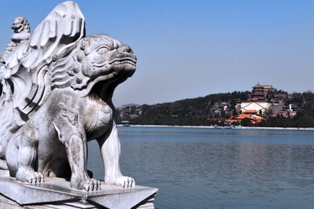 BEIJING - MAR 14:Marble Chinese lion sculpture against the Summer Palace on Kunming Lake  on March 14 2009. The Summer Palace is the best preserved imperial garden in the world.のeditorial素材