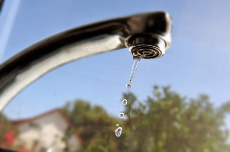 Concept photo of waste of water - leaky water tap in the kitchen.