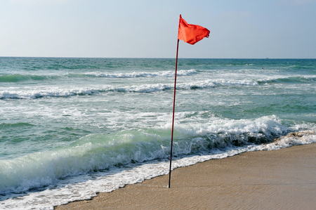 A warning Red flag of danger at sea and no swimming mark posted at the beach.の写真素材