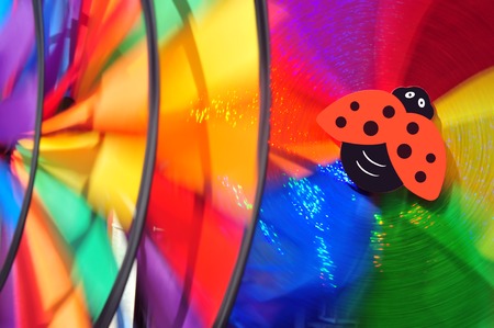 Close up background image of pinwheels spinning in the wind with a toy ladybirdの写真素材