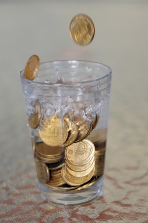 Concept Photo for increasing prices of water - coins falling into a glass full of waterの写真素材