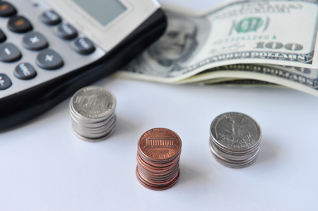 Calculator with American one hundred dollar bills and coins isolated on whiteの写真素材