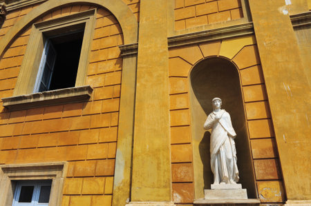 A man looks outside a window near a Roman statue in the Vatican museum Rome Italyのeditorial素材