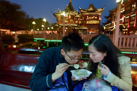 SHANGHAI, CN - MAR 16 2015:Chines couple eats dumpling in Yuyuan Tourist Mart in Shanghai, China.Shanghai Yuyuan Tourist Mart Company Limited, or Yuyuan Tourist Mart, is the largest retailing conglomerate in China.のeditorial素材