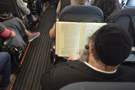 LONDON - MAR 20 2015: Orthodox Jewish men pray on a airplane during flight.Jewish men are obligated to pray three times a day within specific time rangesのeditorial素材