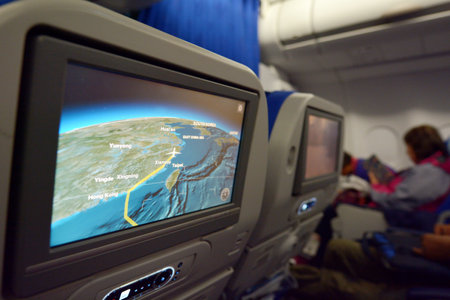SHANGHAI, CN - MAR 15 2015: Interior of airplane with a route on a screen map and a passengers on seats in the background.The annual risk of being killed in a plane crash  is 1 in 11 million.のeditorial素材