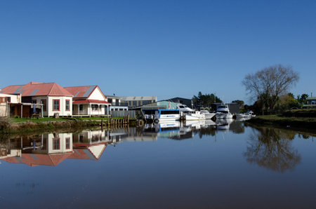Reflection of old ruined houses and boats on a river in Northland New Zealand.のeditorial素材