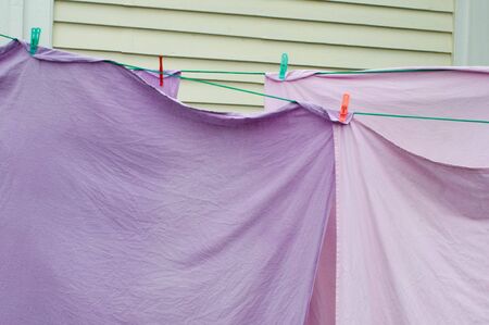 Clean purple and lily color sheets on hanged on a Washing line.の写真素材