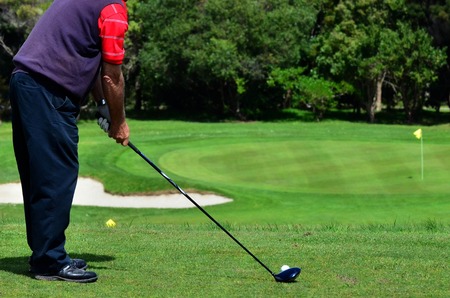 Golfer plays golf in a golf club, prepares to strike a golf ball.の写真素材