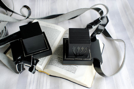 A set of tefillin includes the arm-tefillin (left)and the head-tefillin on a  praying book and Tallit.の写真素材