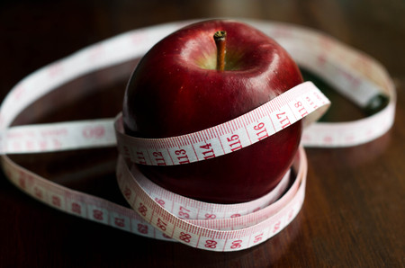 Measuring meter over a diet apple on kitchen table.の写真素材