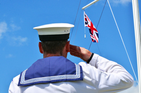 Military navy soldier salute to the flag of the United Kingdom during army parade.の写真素材