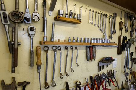 Assortment of do it yourself tools hanging in a wooden cupboard against a wall.の写真素材