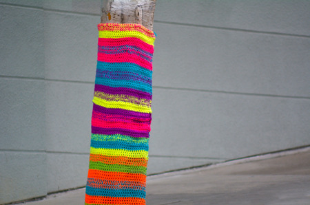 Tree trunk covered with crochet in the street. concept copy space