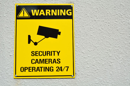 A yellow warning cctv security cameras sign stating that there is cctv cameras in the area operating 24/7. concept with copyspaceの写真素材