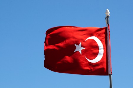 The national flag of Turkey wave in the wind against blue sky.