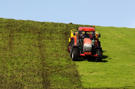 Red tractor plowing the ground in the autumn.