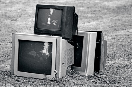 Broken television stacked for disposal outdoor. (BW)