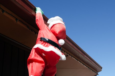 Santa claus climb on a home roof.の写真素材
