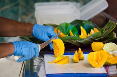 Chef hands slice Papaya fruit in outdoor kitchen on Pacific Island.の写真素材