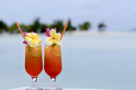 Tropical cocktails served outdoor on Pacific Island resort with turquoise water in the background.の写真素材