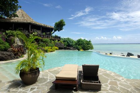 Bach bungalow with empty beach chairs beside a pool in Aitutaki Lagoon Cook Islands