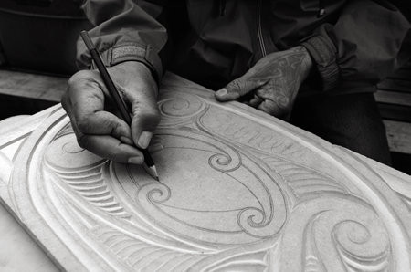 AUCKLAND - AUG 21 2015:Maori man hands drawing patterns of Maori Wood carving.Maori are the indigenous people of New Zealand Originally from Polynesia, migrated to New Zealand over 1000 years ago.のeditorial素材