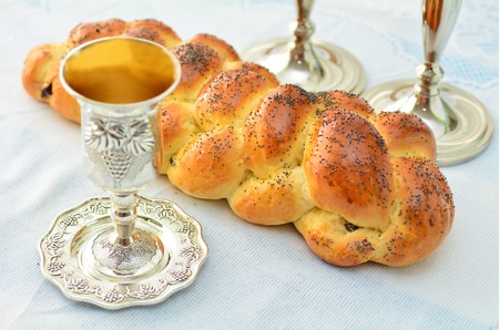 Shabbat eve table with uncovered challah bread, Sabbath candles and Kiddush wine cup.の写真素材