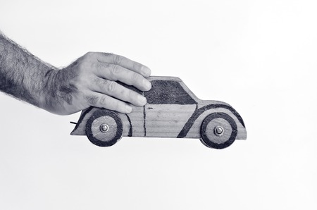 Hand holds toy car isolated on white background - copy space.Concept photo of car business,car Insurance, auto dealership,car rental ,safe driving ,buying, renting, fuel, service and repair costs (BW)の写真素材