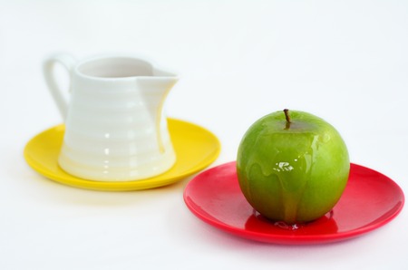 Green apple coverd in honey next to honey pot on Rosh Hashanah Jewish holiday.White background with copy spaceの写真素材
