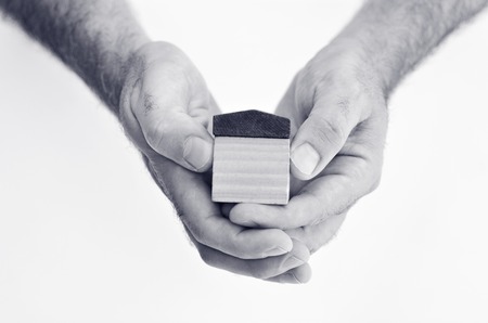 Man hands holds toy house isolated on white background - copy space.Concept photo of real estate business, home Insurance, house rental,buying, renting, mortgage, finance,service and repair costs (BW)の写真素材