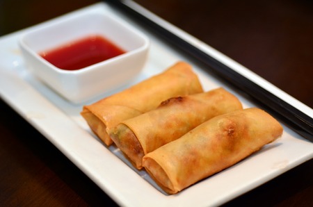 Chines food, Egg rolls served on a plate with chopsticks and Sweet and spicy hot sauce dipping.