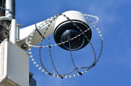 One security surveillance camera protected with barbed wire against vandalism and crime. concept photo of security.の写真素材