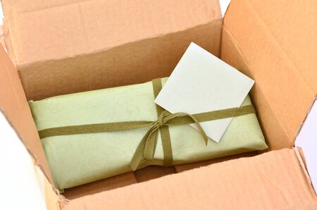 Olive green gift box with dark green ribbon and bow with gift card inside a cardboard delivery...