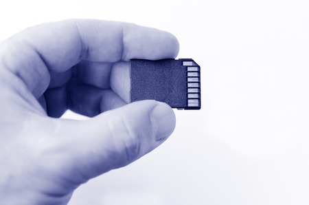 Man hand holds Memory card - Flash card against white background.Concept photo , multimedia, photography,communication, gaming,  lifestyle.  copy space. BWの写真素材
