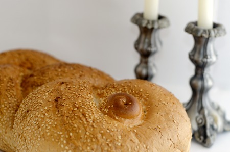 A concept photo of challah bread for the Jewish observance of Shabbat with candles in the...