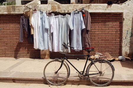 Galabayyas hanging on a clothes line on a street with a bike in Cairo, Egypt.の写真素材