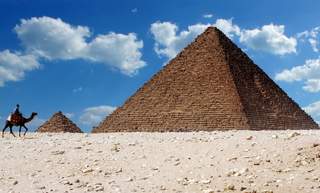 A man riding a camel walks past the iconic pyramids of Giza in Egypt