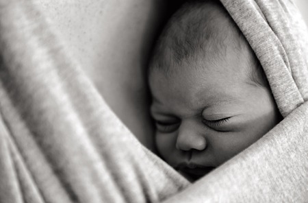 A newborn baby sleep in peace in a baby sling wrap. Copyspace (BW)の写真素材