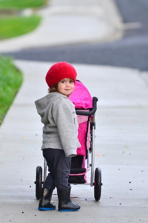 Little girl with baby stroller on the street.の写真素材