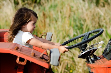 Little girl drive an old tractor.の写真素材