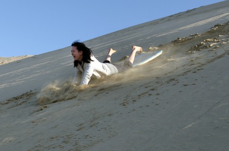 Woman rolled down the slope of snow-white Te Paki sand dunes in Northland New Zealand.の写真素材