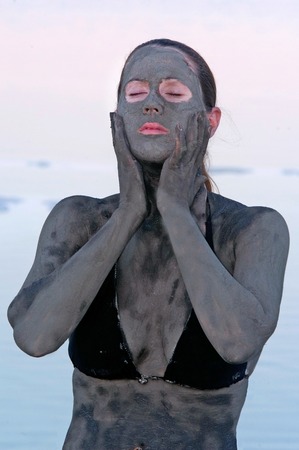 A young woman in a bathing suit is enjoying the natural mineral mud sourced from the Dead Sea,  Israel.の写真素材